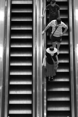 black and white picture of people descending on an escalator