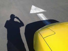 the front of a yellow car and the shadow of a person