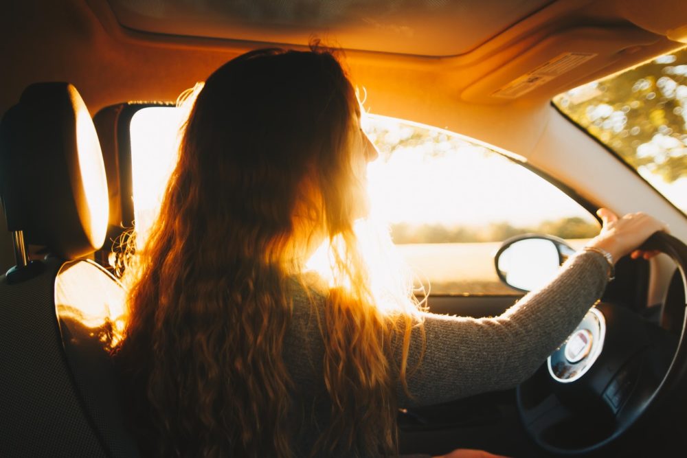 woman driving while the sun is streaming through the window