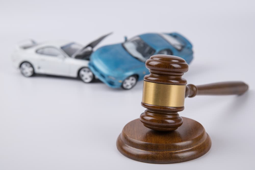 A car collision and a wooden judge's gavel, symbolizing a legal case involving a car accident.