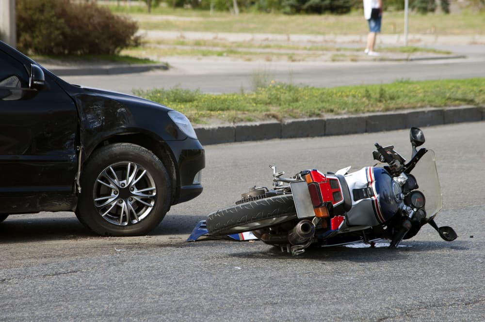 A traffic incident involving an overturned motorcycle and a car with visible damage.