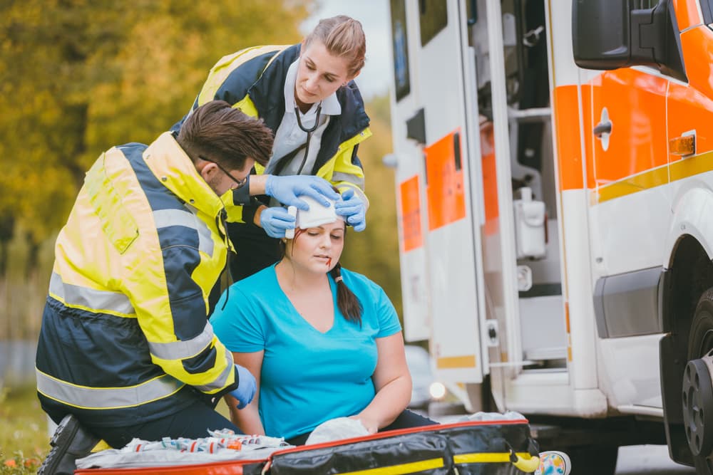 Personal médico de urgencias cura la herida de la cabeza de una mujer herida tras un accidente.