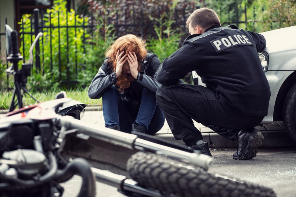 Police officer comforting a distressed individual at a motorcycle accident scene.
