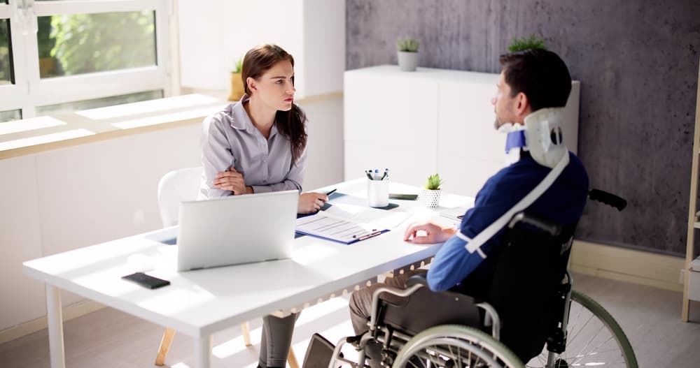 A lawyer and a client in a wheelchair, discussing a motorcycle accident case.